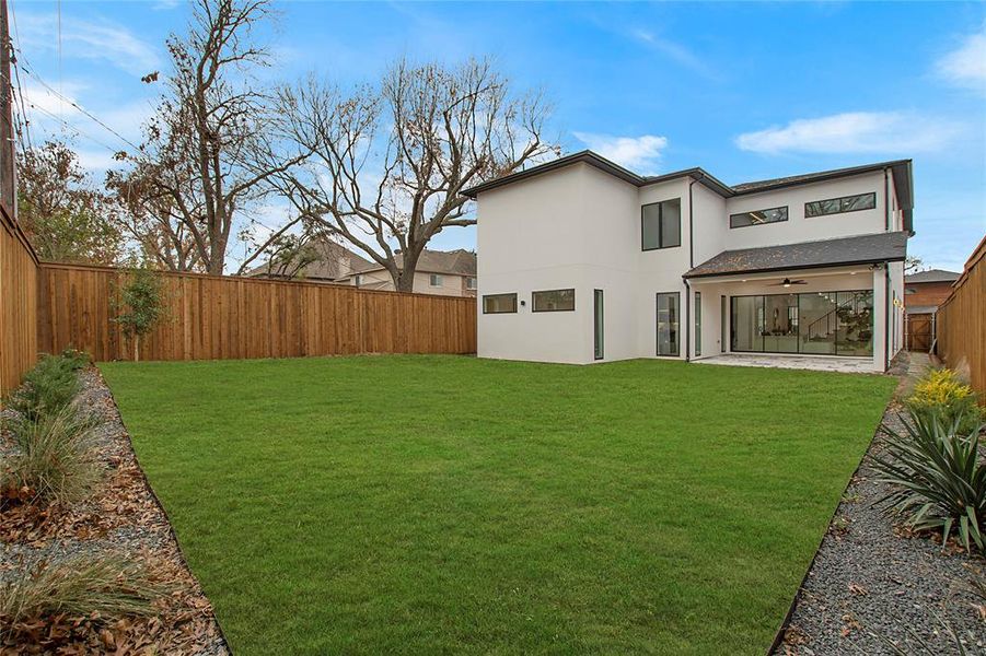 Back of house with a yard and ceiling fan