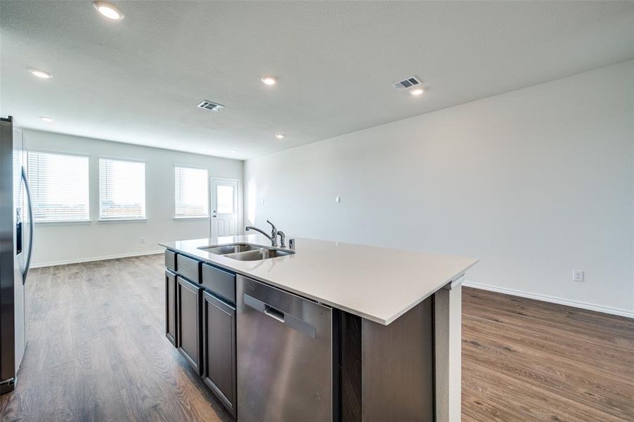 Kitchen featuring sink, hardwood / wood-style flooring, an island with sink, appliances with stainless steel finishes, and dark brown cabinets