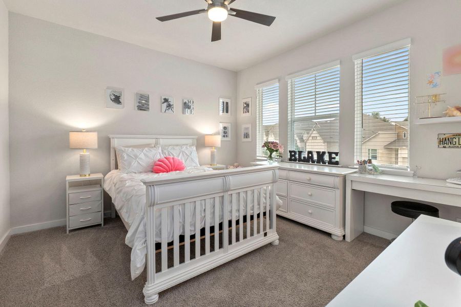 Carpeted room featuring multiple windows with blinds, a ceiling fan, and built-in shelving