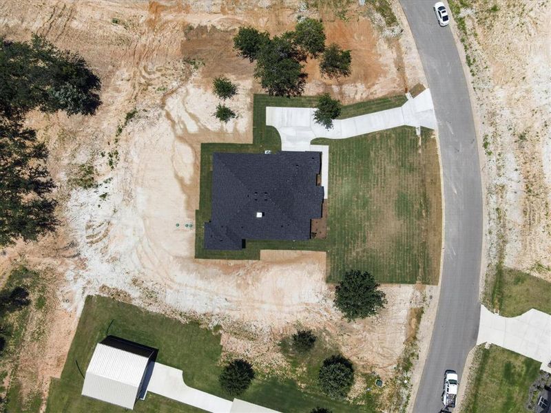 Newly constructed residence with a dark shingle roof, established lawn areas, and a concrete driveway Newly constructed residence with a dark shingle roof, established lawn areas, and a concrete driveway