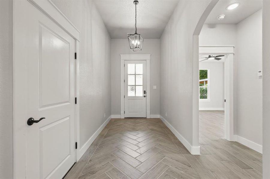 Doorway with arched walkways, baseboards, and a chandelier