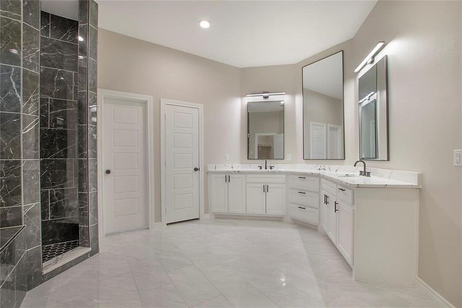 Full bathroom with a marble finish shower, double vanity, and recessed lighting Full bathroom with a marble finish shower, double vanity, and recessed lighting