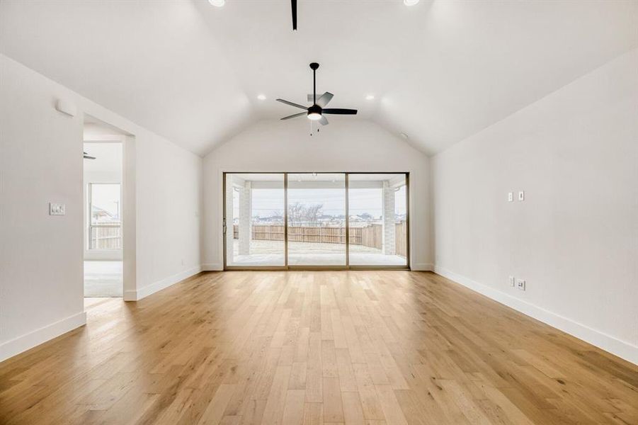 Empty room featuring light wood-type flooring, ceiling fan, vaulted ceiling, and recessed lighting