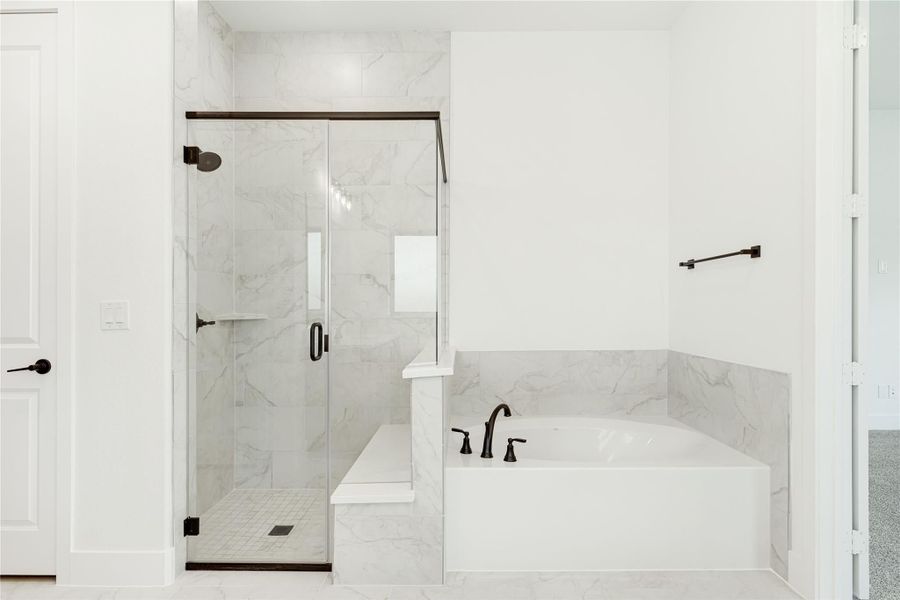 Bathroom with marble tile walk-in shower, glass door, and soaking tub with dark bronze fixtures Bathroom with marble tile walk-in shower, glass door, and soaking tub with dark bronze fixtures