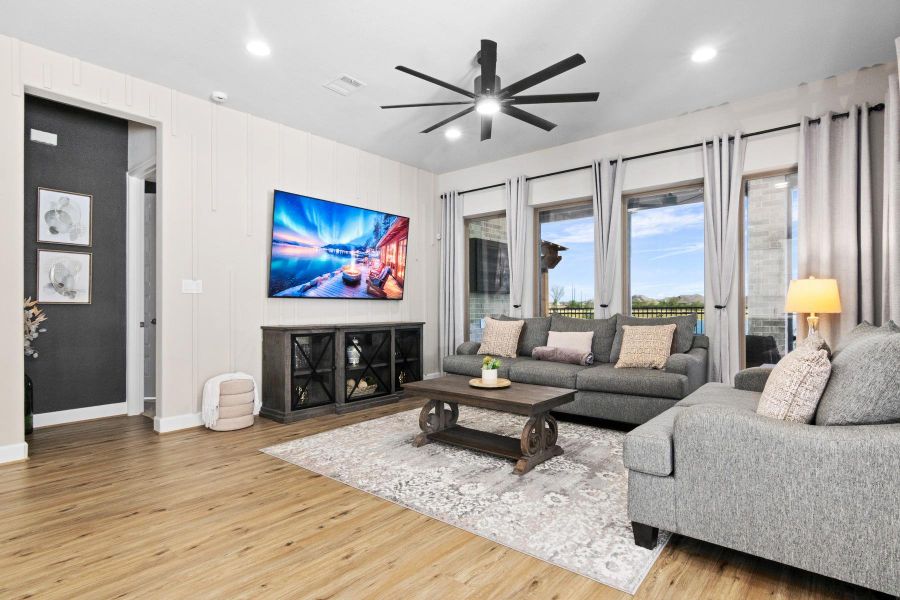 This living room features a modern design with a designer wall finishes, wood flooring, and ample natural light from multiple windows overlooking the gorgeous lake view, while offering a cozy yet elegant atmosphere.