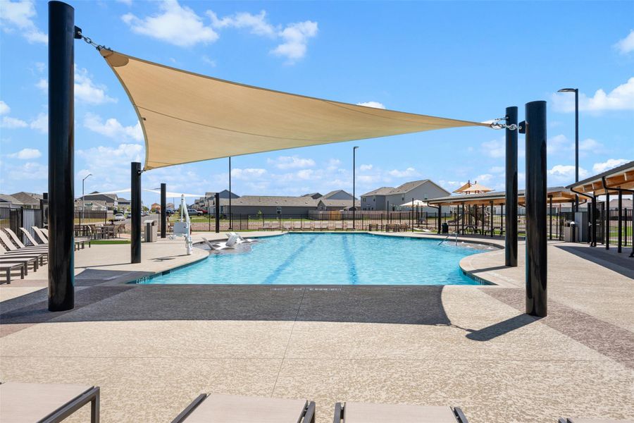 A spacious community swimming pool is shaded by a large sail canopy on sunny days. A spacious community swimming pool is shaded by a large sail canopy on sunny days.