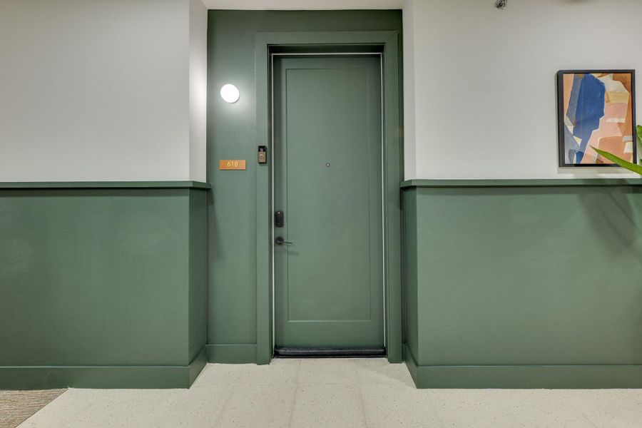 The property features a private entrance door with a modern black handle, complemented by a round wall light