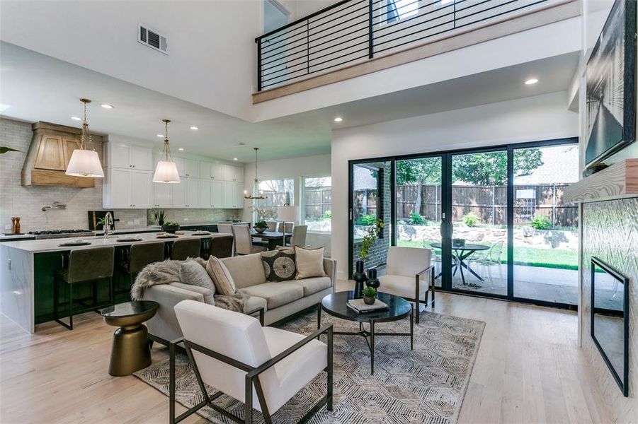 Living room featuring a towering ceiling, plenty of natural light, and light wood-type flooring