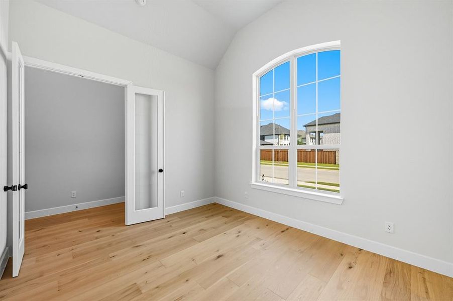 Spare room featuring light wood-style floors, lofted ceiling, and a residential view