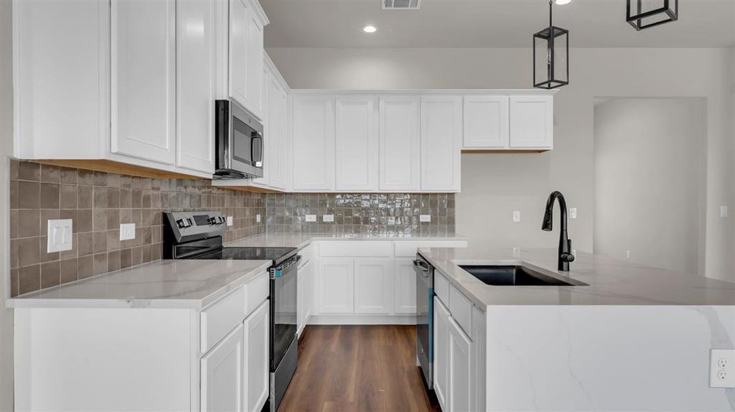 Crisp white cabinetry contrasts beautifully with rich wood-look flooring and a tiled backsplash. Crisp white cabinetry contrasts beautifully with rich wood-look flooring and a tiled backsplash.