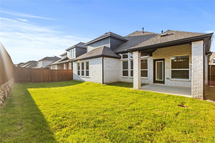 Rear view of house featuring a patio and a lawn