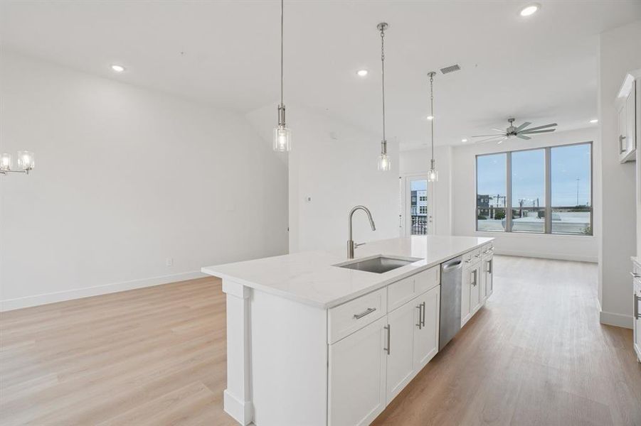 Kitchen with white cabinetry, open floor plan, light wood finished floors, a kitchen island with sink, and recessed lighting