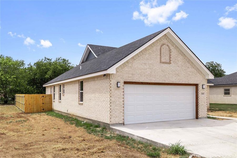 View of property exterior featuring brick siding, roof with shingles, concrete driveway, and a garage View of property exterior featuring brick siding, roof with shingles, concrete driveway, and a garage