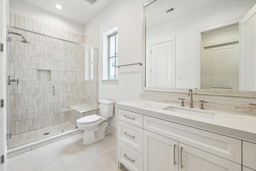 Full bath off secondary features glass enclosed shower with seat.