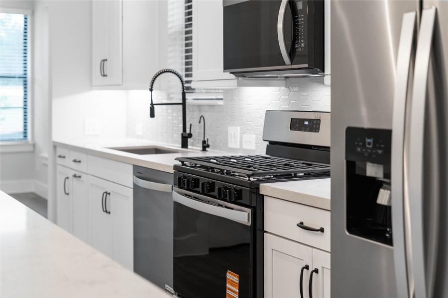 The premium stainless steel culinary suite features a spacious french-door refrigerator with a built-in ice and water dispenser, a high-performance gas range with a matching over-the-range microwave, and an integrated dishwasher. The premium stainless steel culinary suite features a spacious french-door refrigerator with a built-in ice and water dispenser, a high-performance gas range with a matching over-the-range microwave, and an integrated dishwasher.