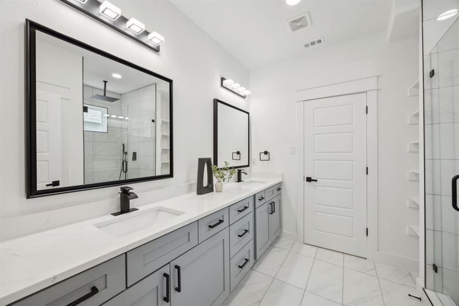 Primary bathroom with dual vanity, tile patterned floors, and a shower