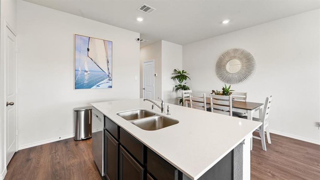 Kitchen with dark wood-style flooring, a kitchen island with sink, recessed lighting, stainless steel dishwasher, and dark cabinetry