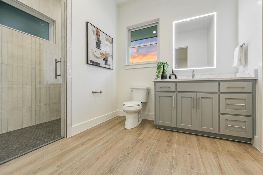 Full bath with vanity, a shower stall, and light wood-style flooring