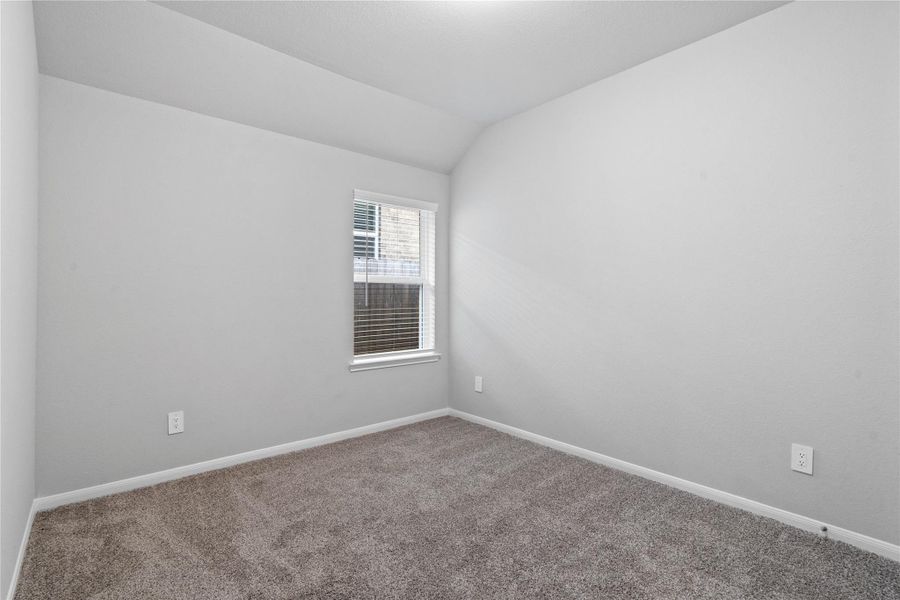 This cozy secondary bedroom offers plush soft carpeting, neutral walls ready for personalization, a sun-filled window with fitted blinds, sloped ceilings, and a spacious closet for all your storage needs.