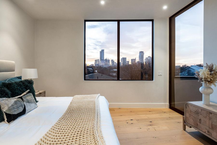 Floor-to-ceiling windows frame a dynamic cityscape in this refined bedroom. Floor-to-ceiling windows frame a dynamic cityscape in this refined bedroom.