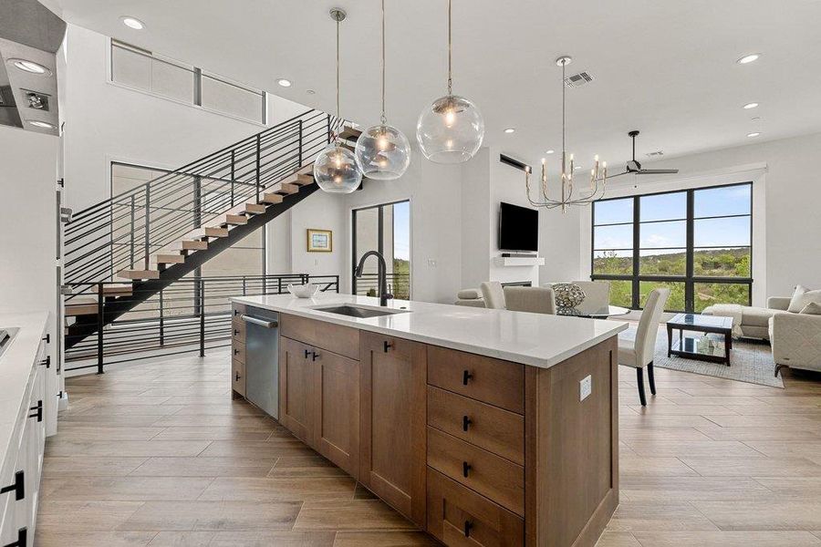 Open-concept living space featuring a central kitchen island with a white countertop and wood-finish cabinetry