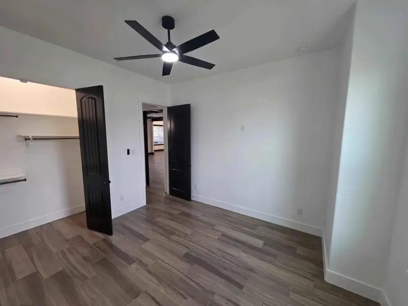 Unfurnished bedroom featuring dark wood-type flooring, ceiling fan, and a closet Unfurnished bedroom featuring dark wood-type flooring, ceiling fan, and a closet