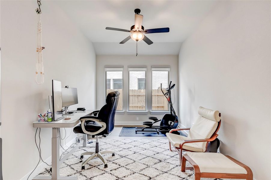 A versatile room combines productive workspace with fitness amenities, bathed in natural light from ample windows.