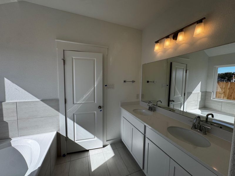 Full bath with a garden tub, double vanity, and dark tile patterned floors Full bath with a garden tub, double vanity, and dark tile patterned floors