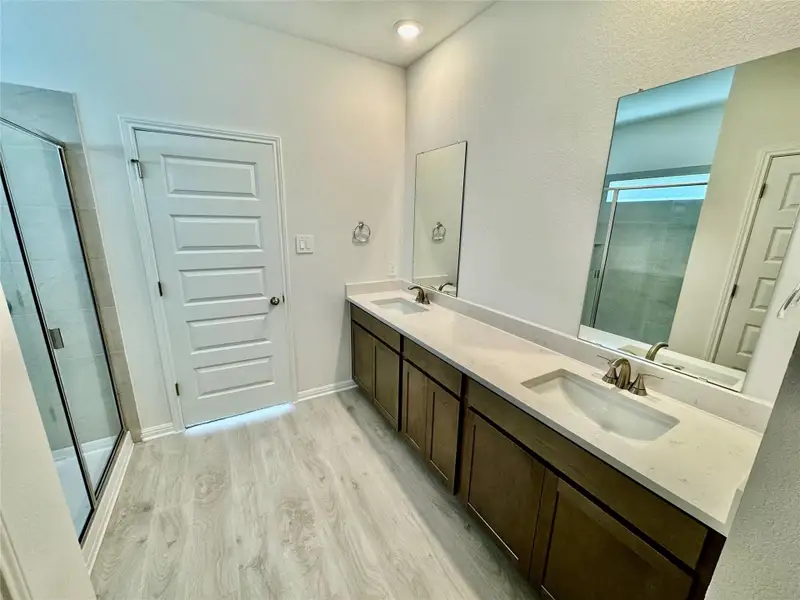 Full bathroom with wood finished floors, double vanity, and a shower stall Full bathroom with wood finished floors, double vanity, and a shower stall