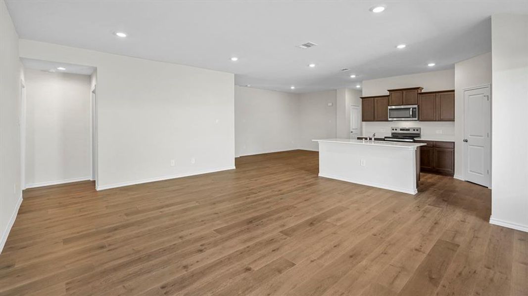 Kitchen with an island with sink, open floor plan, recessed lighting, stainless steel appliances, and dark wood finish cabinetry