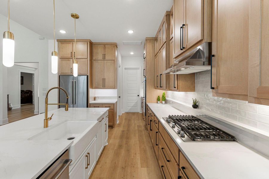 Notice the farmhouse sink, generous cabinet storage and sleek gas cooktop!