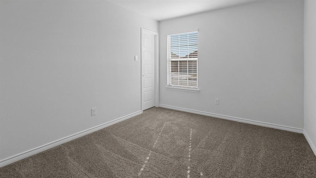 Carpeted spare room featuring baseboards