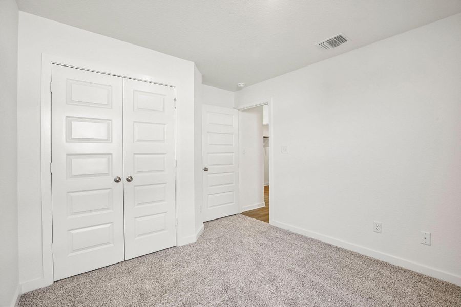 Plush carpeting anchors this versatile bedroom space complete with clean lines and classic paneled doors.