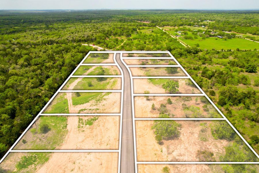 An aerial perspective reveals a subdivision of cleared lots nestled amidst a verdant landscape.
