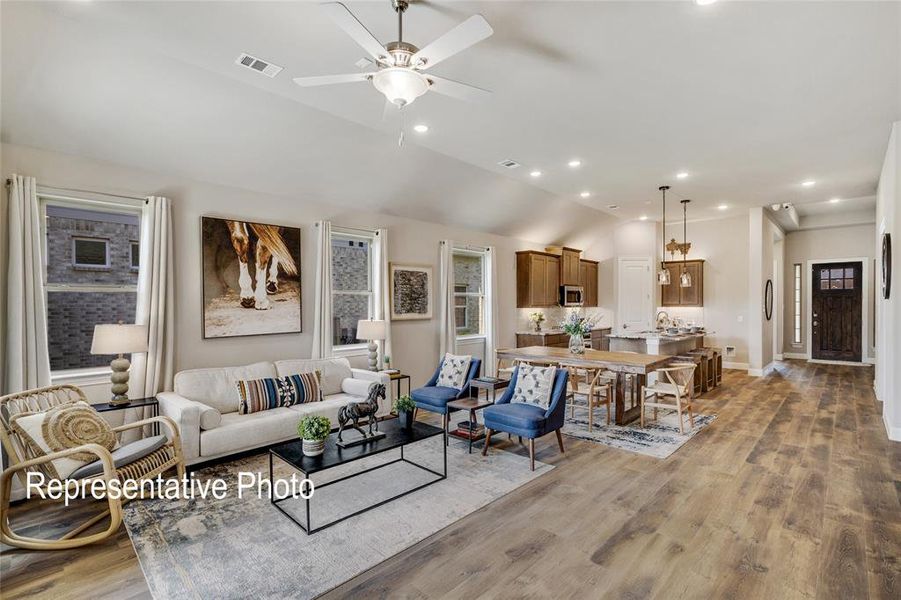 Living room with hardwood / wood-style flooring, ceiling fan, and vaulted ceiling