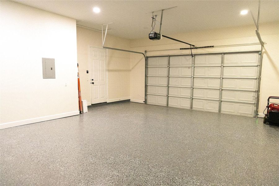 Garage featuring electric panel, a garage door opener, and recessed lighting
