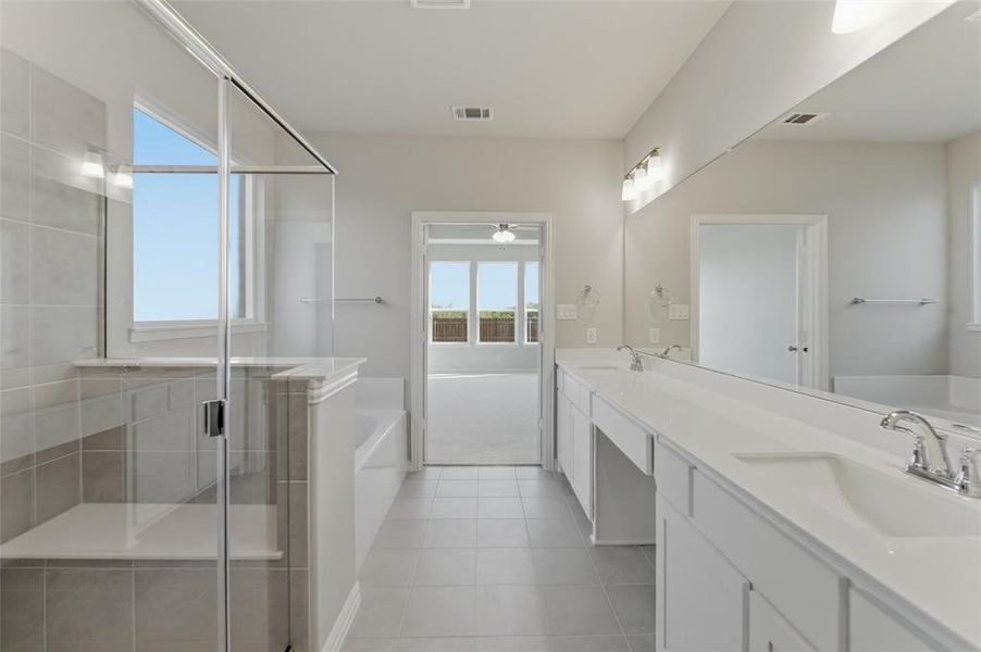 Bathroom with a bath, double vanity, a stall shower, light tile patterned floors, and light colored carpet