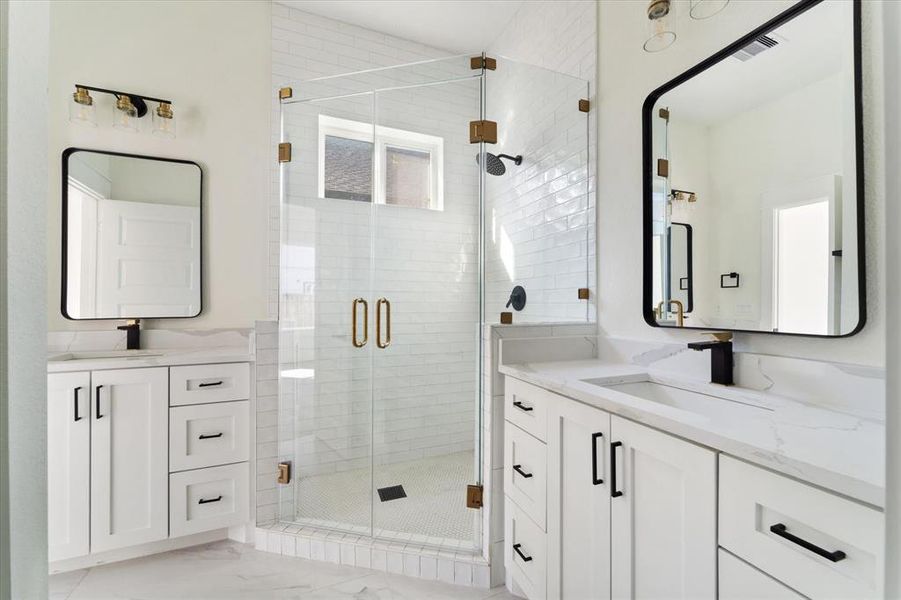 This primary bath offers dual sinks, plenty of under the counter storage and a huge walk in shower enclosed with glass.