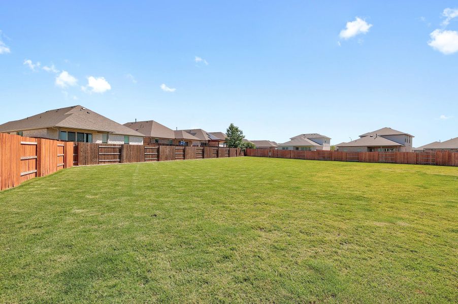 Expansive green lawn with a newly installed wood privacy fence enclosing the property Expansive green lawn with a newly installed wood privacy fence enclosing the property