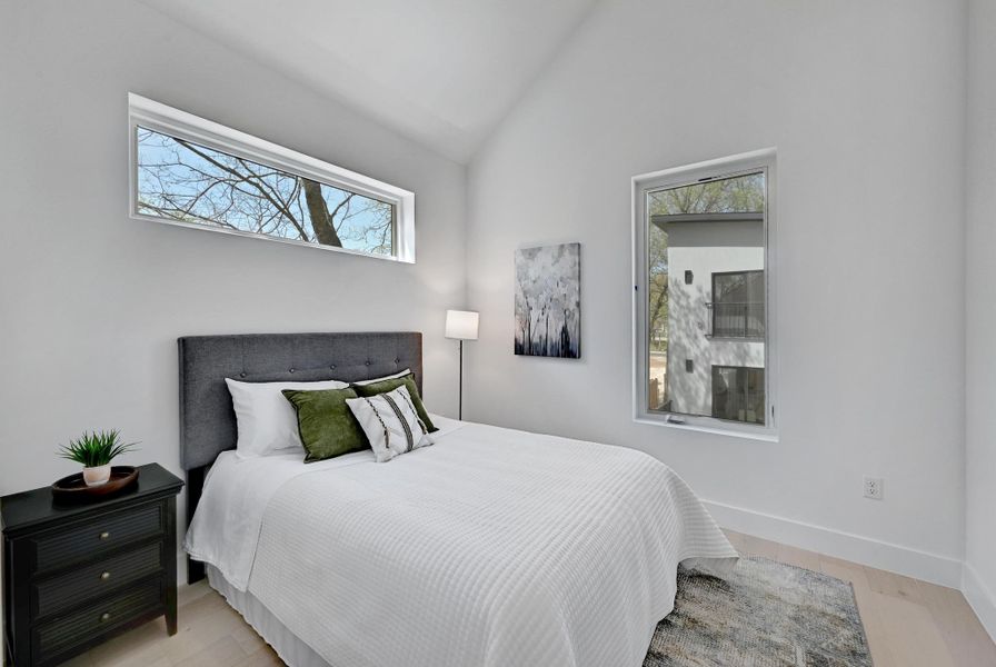 Bedroom featuring light wood-type flooring, baseboards, and vaulted ceiling