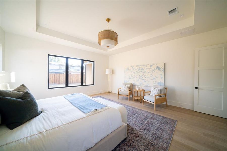 Bedroom with light wood-type flooring and a raised ceiling