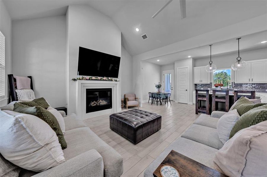Spacious open-concept living area featuring a vaulted ceiling and light wood-finish flooring