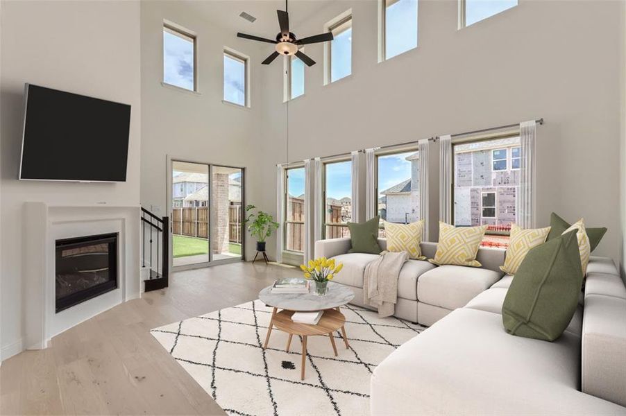 Virtually Staged Photo - Living room with a healthy amount of sunlight, a high ceiling, ceiling fan, and light wood-type flooring