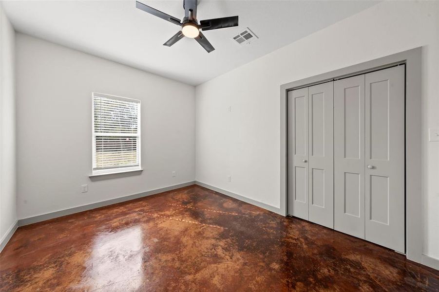 Unfurnished bedroom with concrete floors, a closet, and ceiling fan
