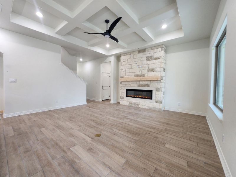 Spacious living area featuring a stone-clad fireplace with a recessed electric insert, a wood mantel, and wood-finish flooring