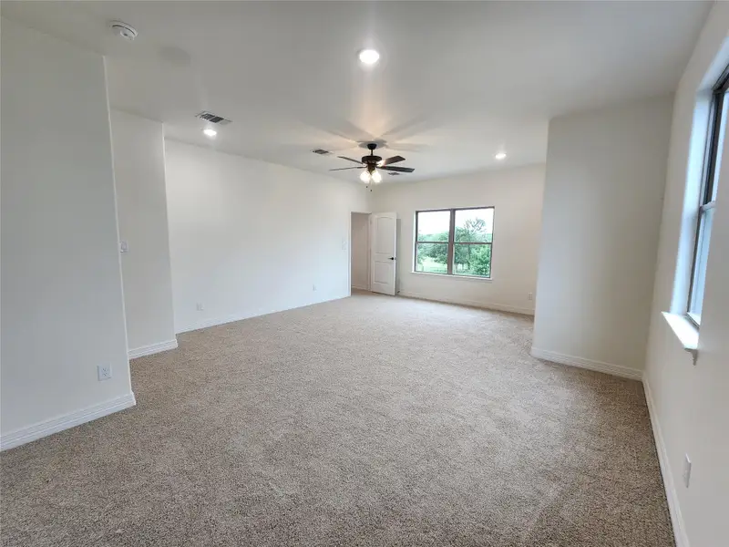 Spacious room featuring neutral carpeting, a ceiling fan with integrated lighting, recessed lighting, and white baseboards