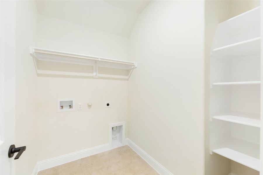 Laundry room with washer and dryer hookups, upper hanging rod, and built-in shelving on tile floor Laundry room with washer and dryer hookups, upper hanging rod, and built-in shelving on tile floor