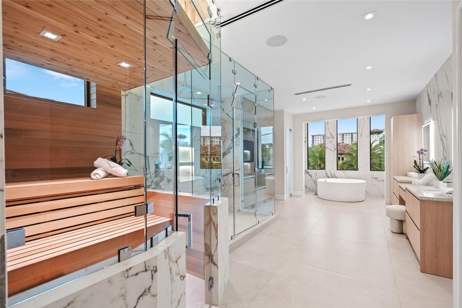 Luxurious primary bathroom retreat with a glass-enclosed sauna, spa shower, freestanding soaking tub, and dual vanities with modern finishes. Luxurious primary bathroom retreat with a glass-enclosed sauna, spa shower, freestanding soaking tub, and dual vanities with modern finishes.