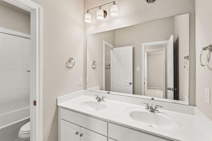 The secondary bath features tile flooring, white cabinetry and light countertops and a shower/tub combo. Perfect for accommodating any visiting family and friends.