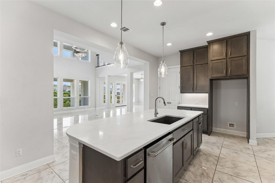 A well-lit kitchen island with a sink offers ample counter space, overlooking an airy open-concept living area.